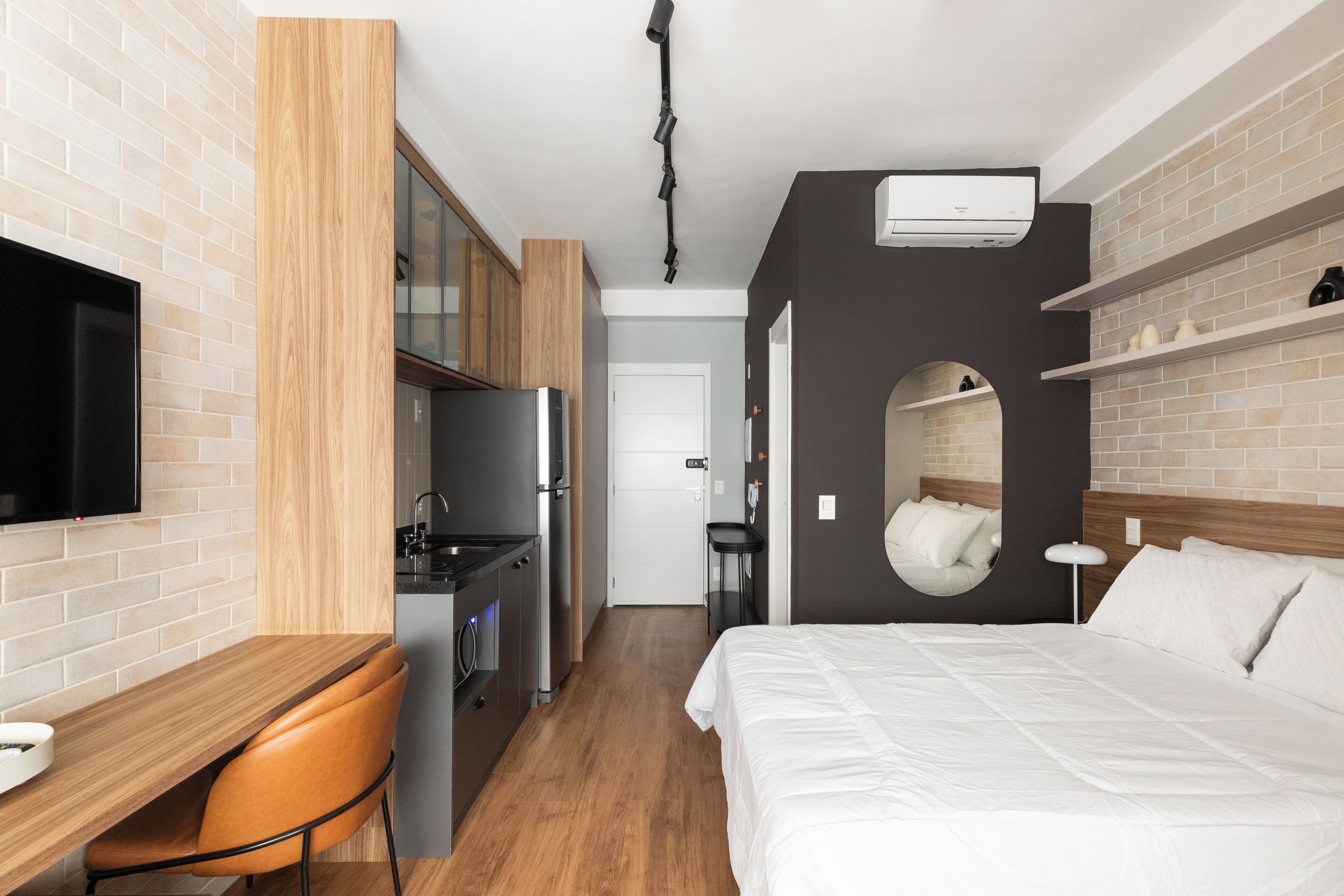 Quarto de hotel compacto com cozinha compacta, cama, escrivaninha e televisão.