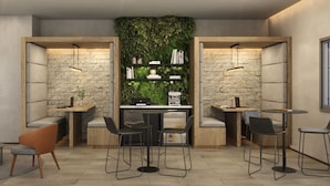 A modern cafe with a central counter, two seating areas, and a green wall with plants. - Haus Mitre Vila Clementino by Wecare (São Paulo)