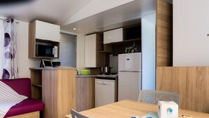 Una kitchenette compacta equipada con microondas, estufa y refrigerador. Cuenta con una mesa de comedor con sillas y un pequeño sofá.
