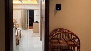 Een deuropening die leidt naar een goed verlichte kamer met een plafondventilator, een eethoek met een tafel en stoelen, en een schoenenrek.