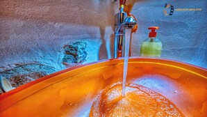Un lavamanos con agua corriendo, un dispensador de jabón y un grifo.