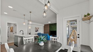 A modern kitchen with white cabinetry, a dark wooden dining table, and pendant lighting. - Bright, new suite 10 min from Calgary (Okotoks)