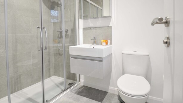 A modern bathroom with a glass-enclosed shower, a white sink, and a toilet. - 20 Meadow Retreat (Liskeard)