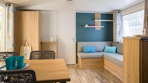 Una habitación compacta con una mesa de madera, un sofá con cojines y una pequeña estantería con objetos.