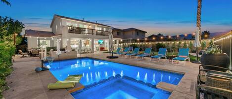 A swimming pool with lounge chairs and a two-story building in the background.