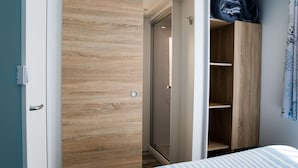 A bedroom with a wooden wardrobe, a bed with striped bedding, and a blue and white striped curtain. - Palmyre - Confort 3 - 7p (30) (Les Mathes)