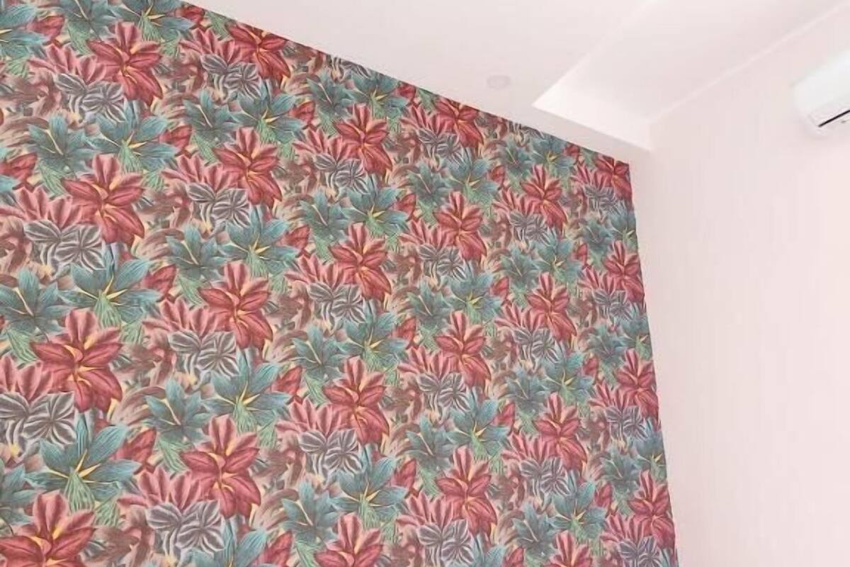 A bedroom with a floral wallpaper, a bed with white bedding, and a wooden headboard.