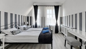 A bedroom with two beds, striped walls, a window with curtains, a bedside table, and a bench. - Louise Apartment Old Town Długa Street (Gdańsk)