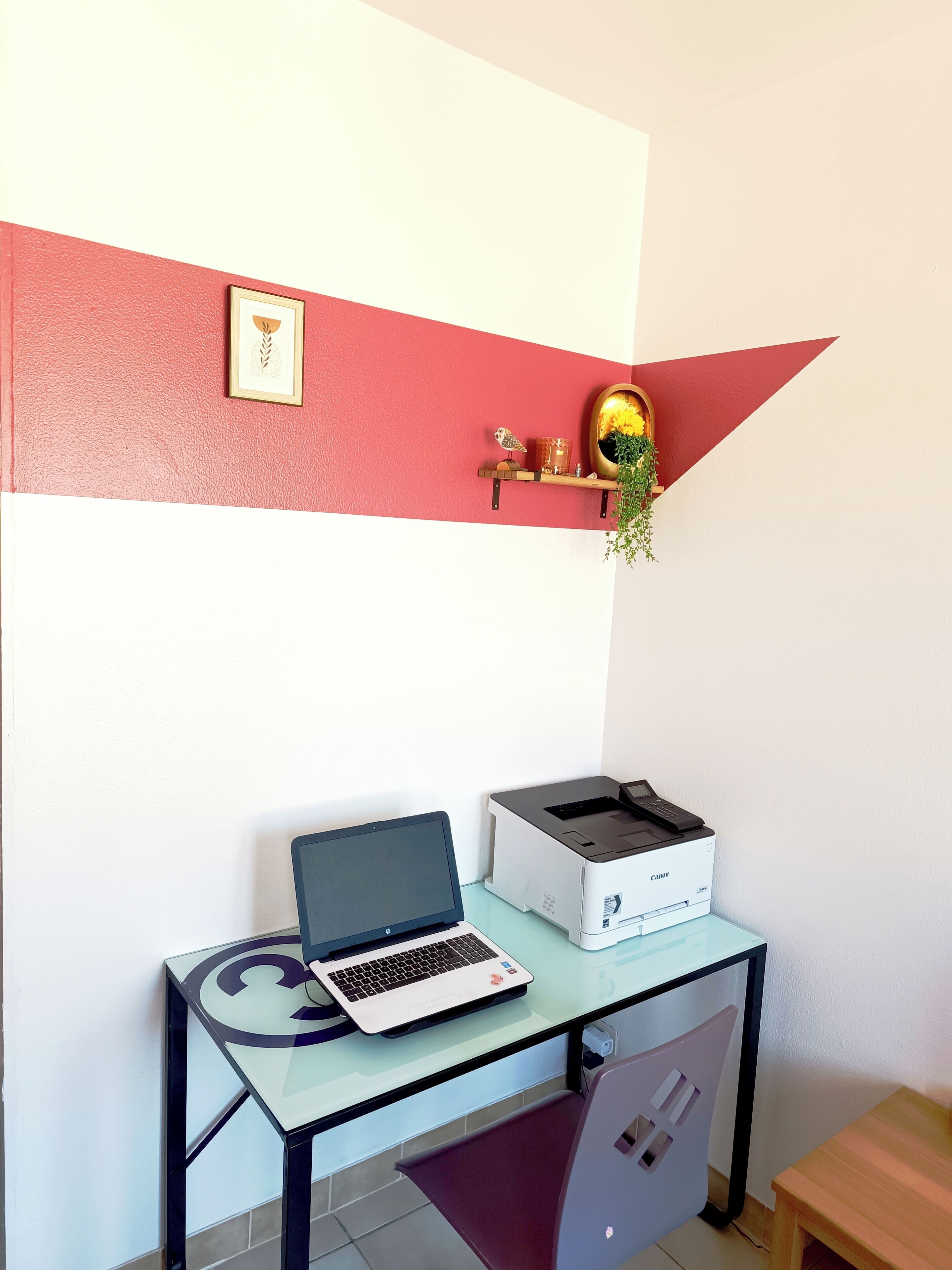 Ein Arbeitsplatz mit Laptop, Drucker und einer kleinen Ablagefläche mit Dekoration.