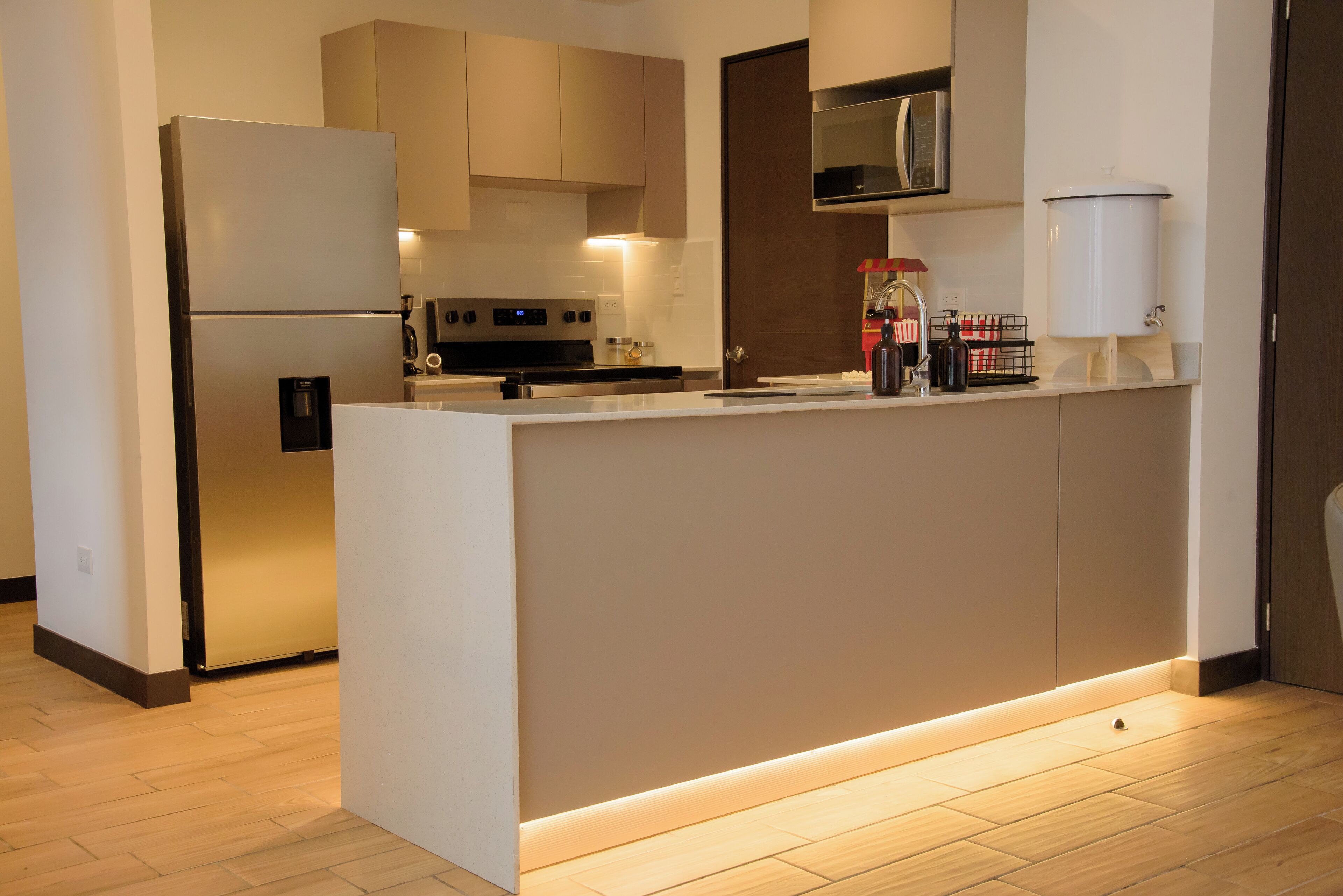 Una cocina moderna con una isla integrada, electrodomésticos de acero inoxidable y un microondas sobre la encimera.