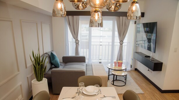 A modern living room with a dining area, a sofa, a TV, and a plant.