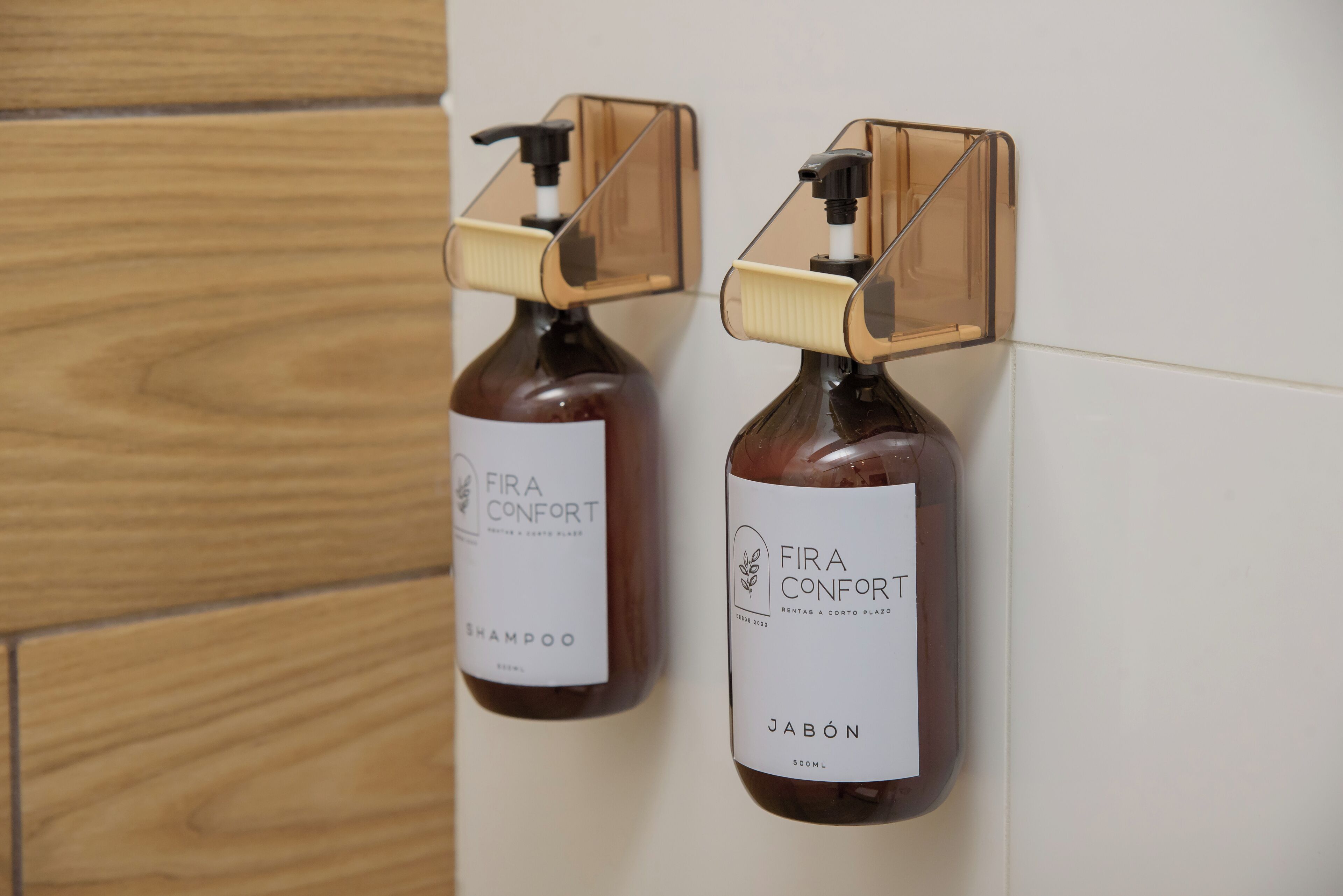 Duas embalagens de shampoo e gel de banho Fira Confort penduradas numa parede.