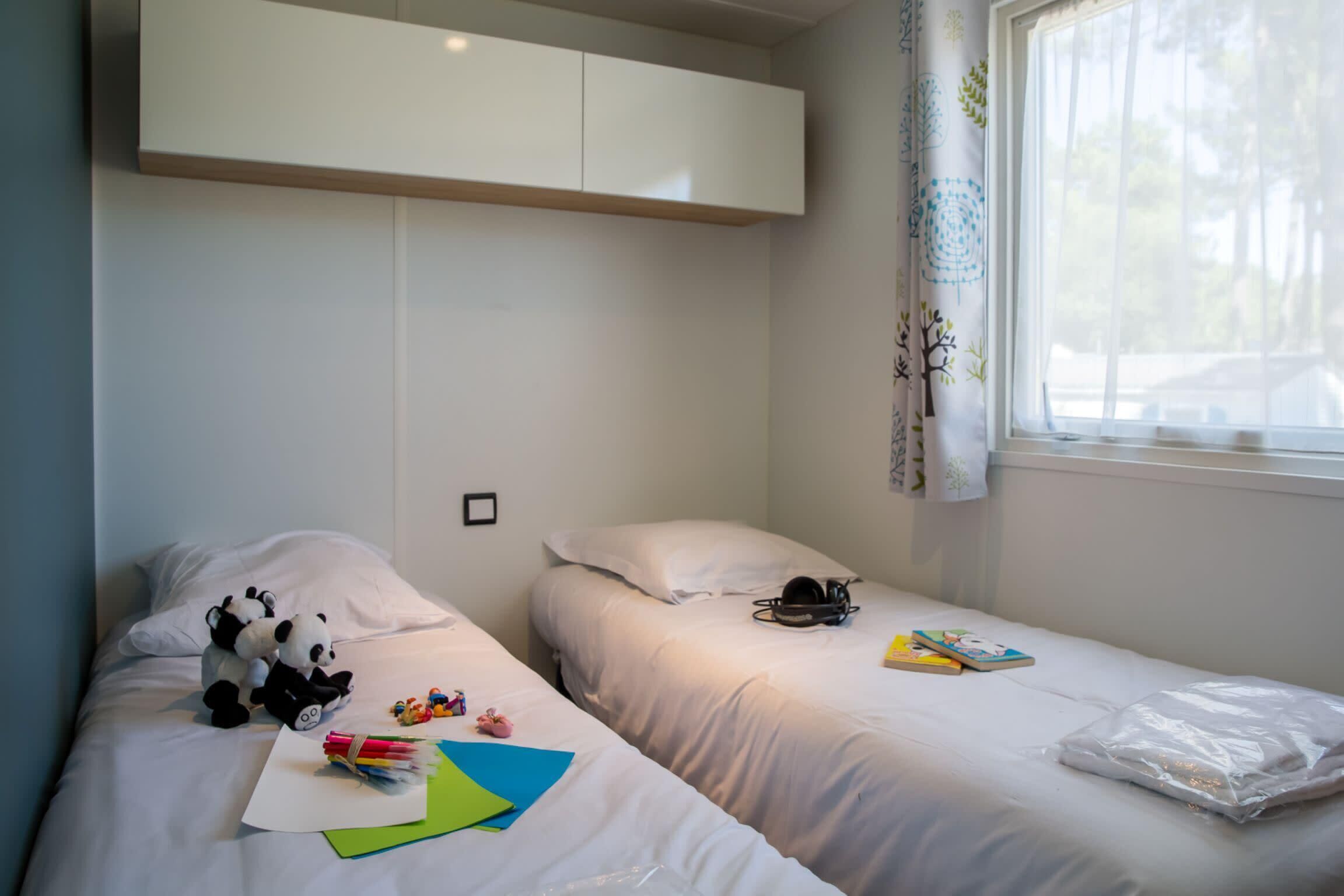 Une chambre avec deux lits, une armoire et une fenêtre avec des rideaux.