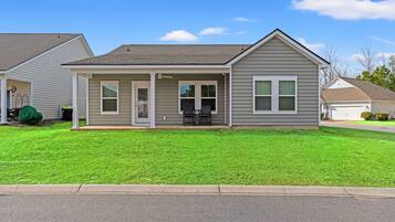 A single-story house with a covered porch, a front yard, and a driveway.