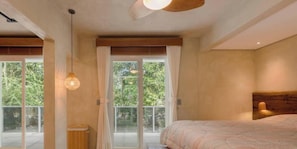 A bedroom with a bed, a ceiling fan, a window with curtains, and a view of greenery outside.