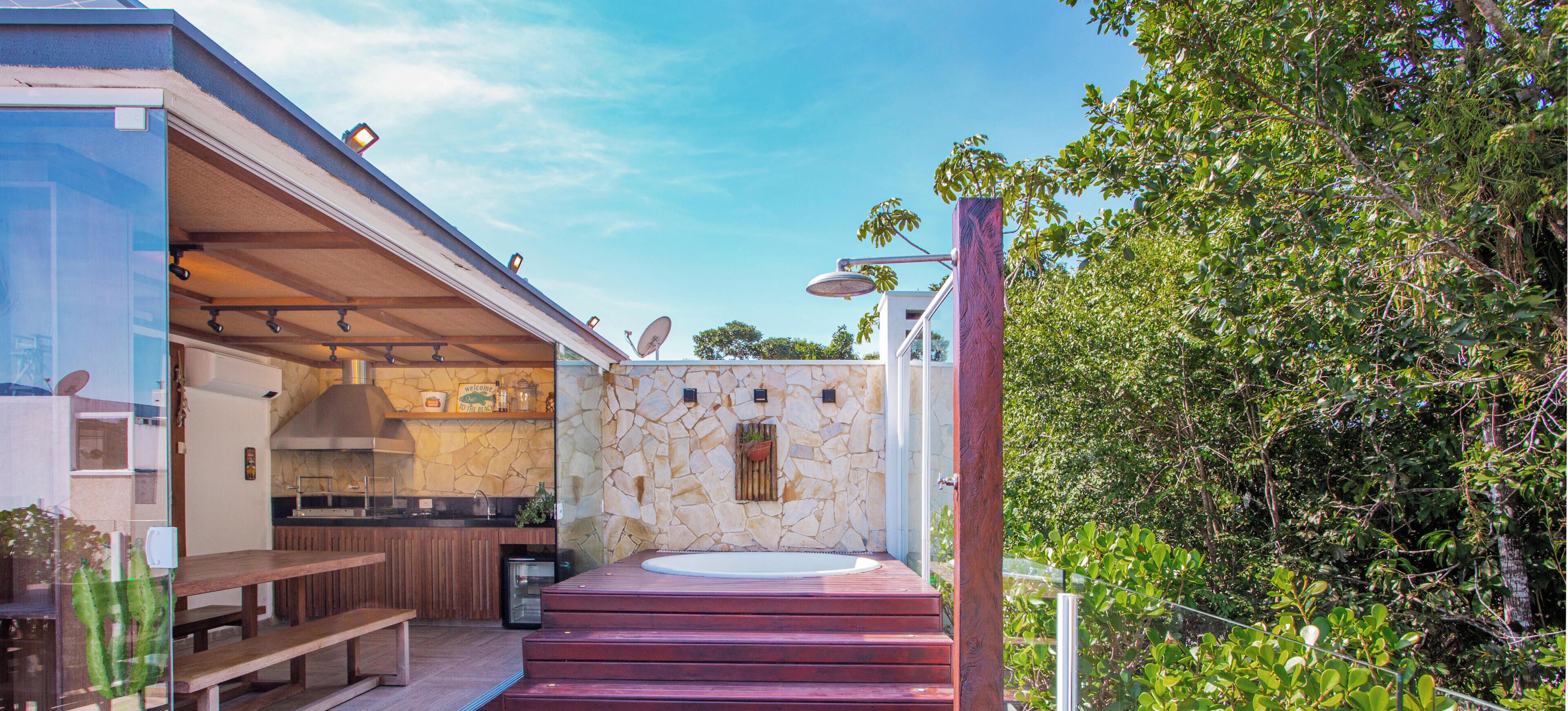 Una cocina al aire libre moderna con pared de piedra, un jacuzzi y una terraza de madera.