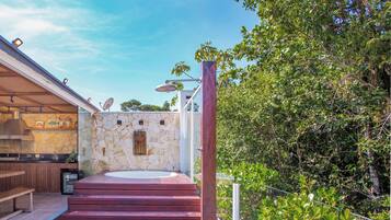 Una cocina al aire libre moderna con pared de piedra, un jacuzzi y una terraza de madera.