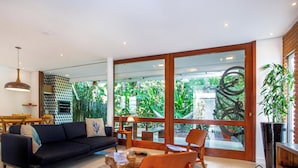 A modern living room with a sofa, chairs, a coffee table, and a dining area. - Casa com jacuzzi e rooftop by Wecare (Bertioga)