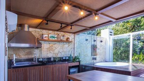 A modern kitchen with a stone backsplash, wooden counter, and a large window overlooking greenery. - Casa com jacuzzi e rooftop by Wecare (Bertioga)