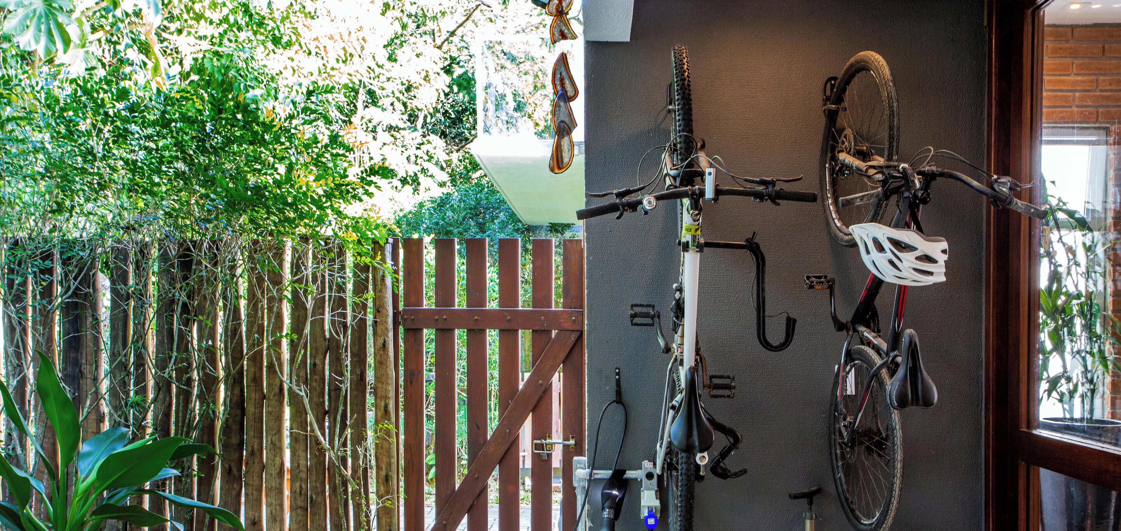 Una bicicleta colgada en una pared, una valla de madera y una ventana con vistas a la vegetación.