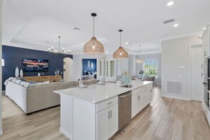 A modern kitchen with white cabinetry, a central island, and pendant lighting. - New Home w/ Pool at The National in Ave Maria FL (Ave Maria)