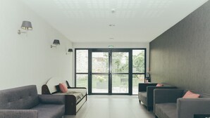 Un área de espera moderna con dos sofás, una mesa de centro y un gran ventanal que da al exterior.