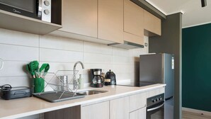 Una cocina moderna con armarios de madera clara, un refrigerador de acero inoxidable, un horno empotrado y una cafetera.