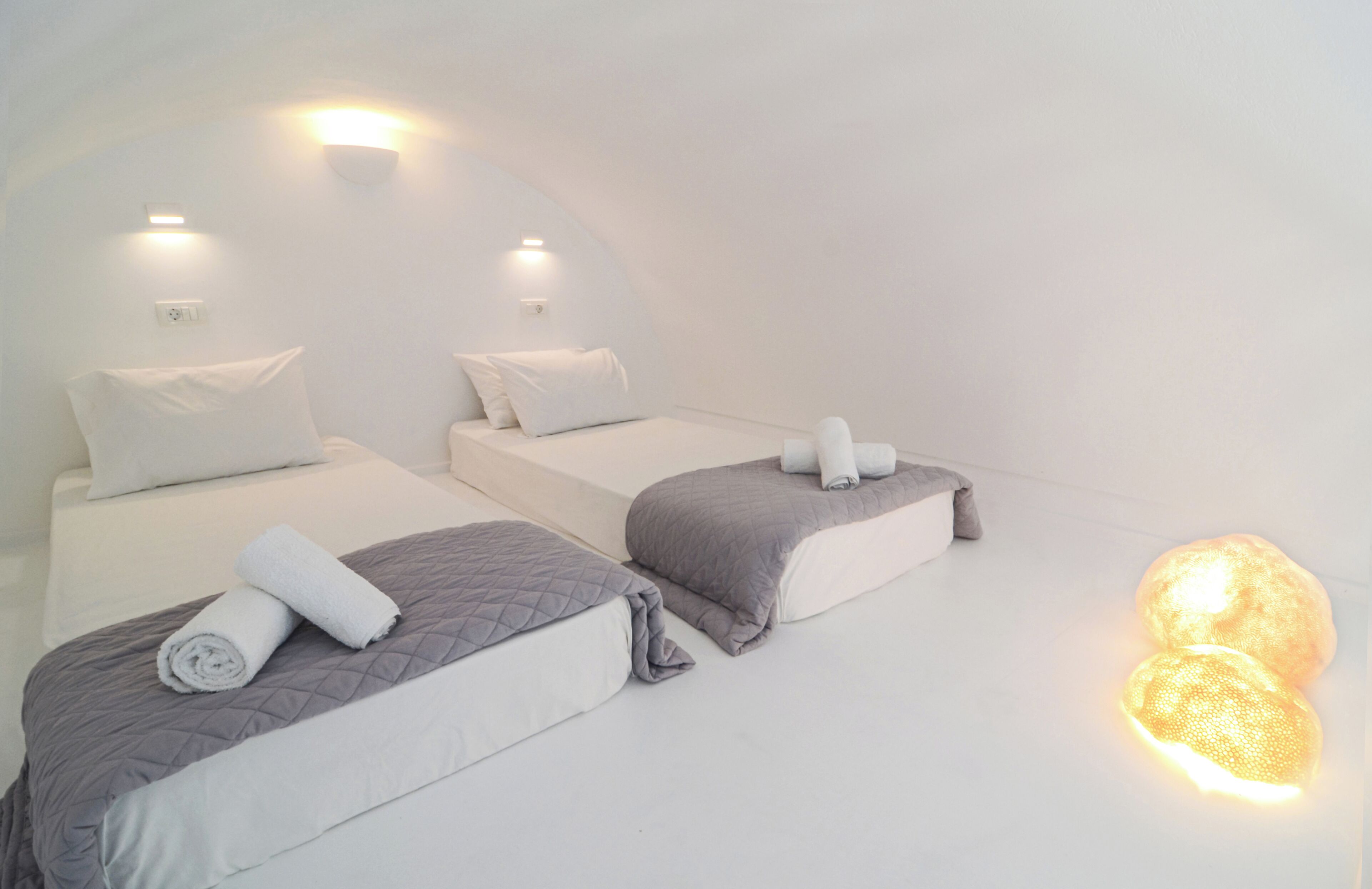 A hotel room with two beds, each with a pillow and a rolled towel.