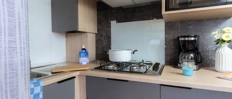 Una cocina moderna con estufa a gas, microondas y cafetera.