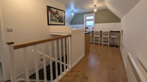 A staircase leading to a kitchen with a window, a framed picture on the wall, and a ceiling fan. - Digby house flat 2 (West Mersea)
