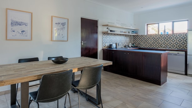 A modern kitchen with a wooden dining table and chairs, a built-in island, and patterned backsplash. - 2stay-Aparments (Cape Town)