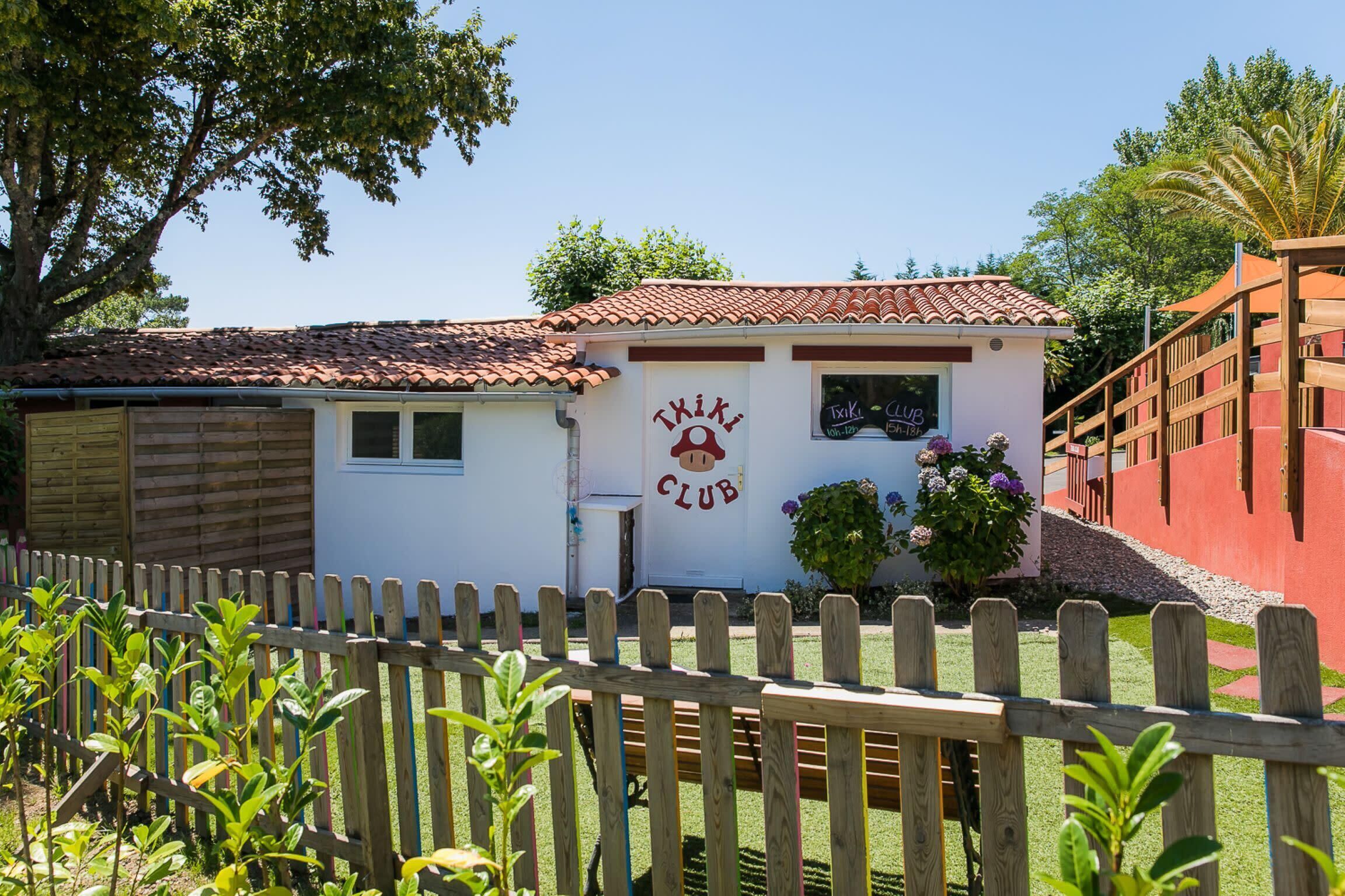 Um edifício com uma placa que diz "TIKI CLUB" e uma cerca de madeira em primeiro plano.