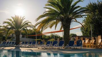 A pool area with lounge chairs and palm trees.