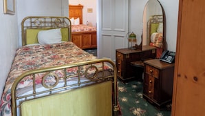 A bedroom with a bed, a dresser, a mirror, and a door leading to another room.