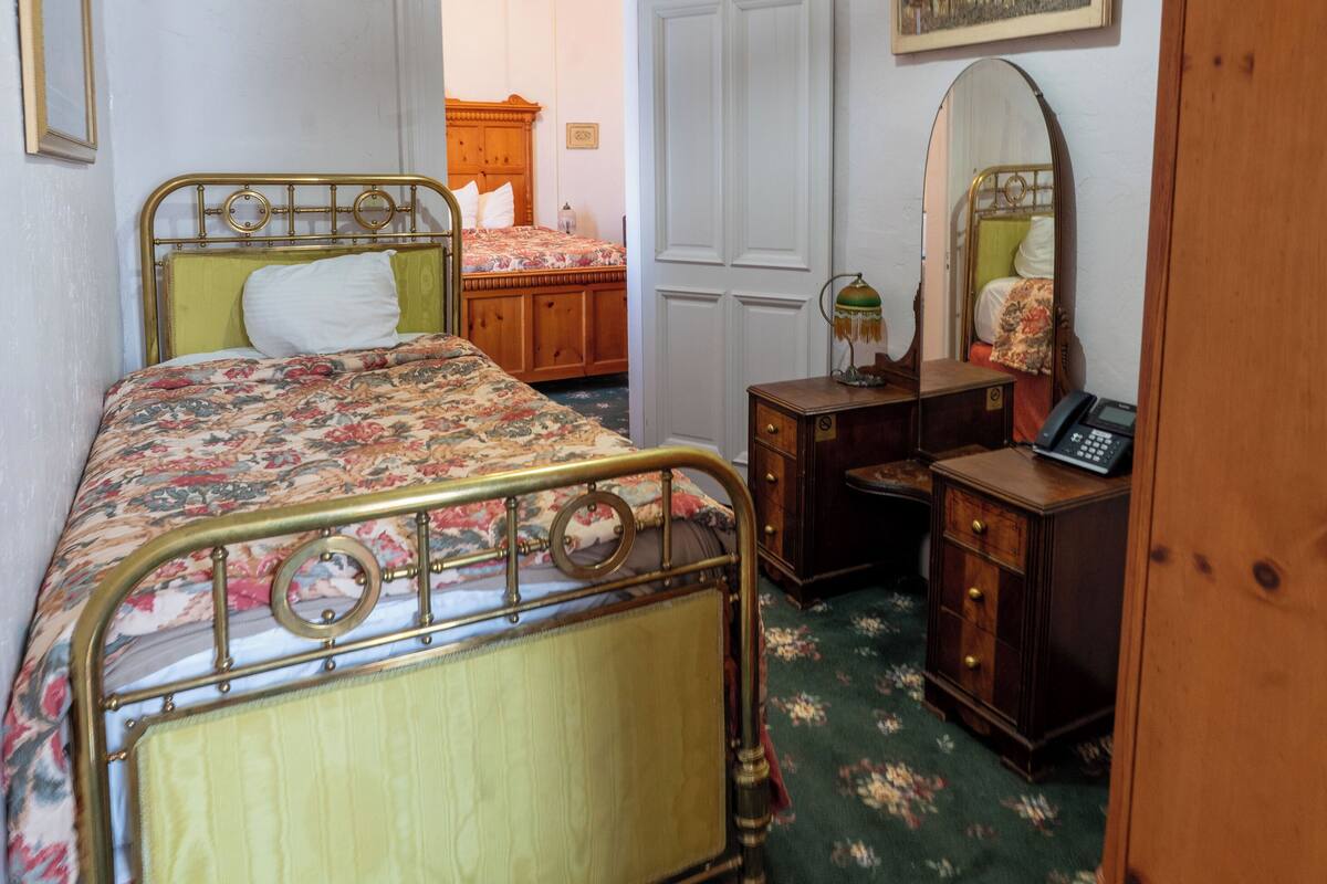 A bedroom with a bed, a dresser, a mirror, and a door leading to another room.