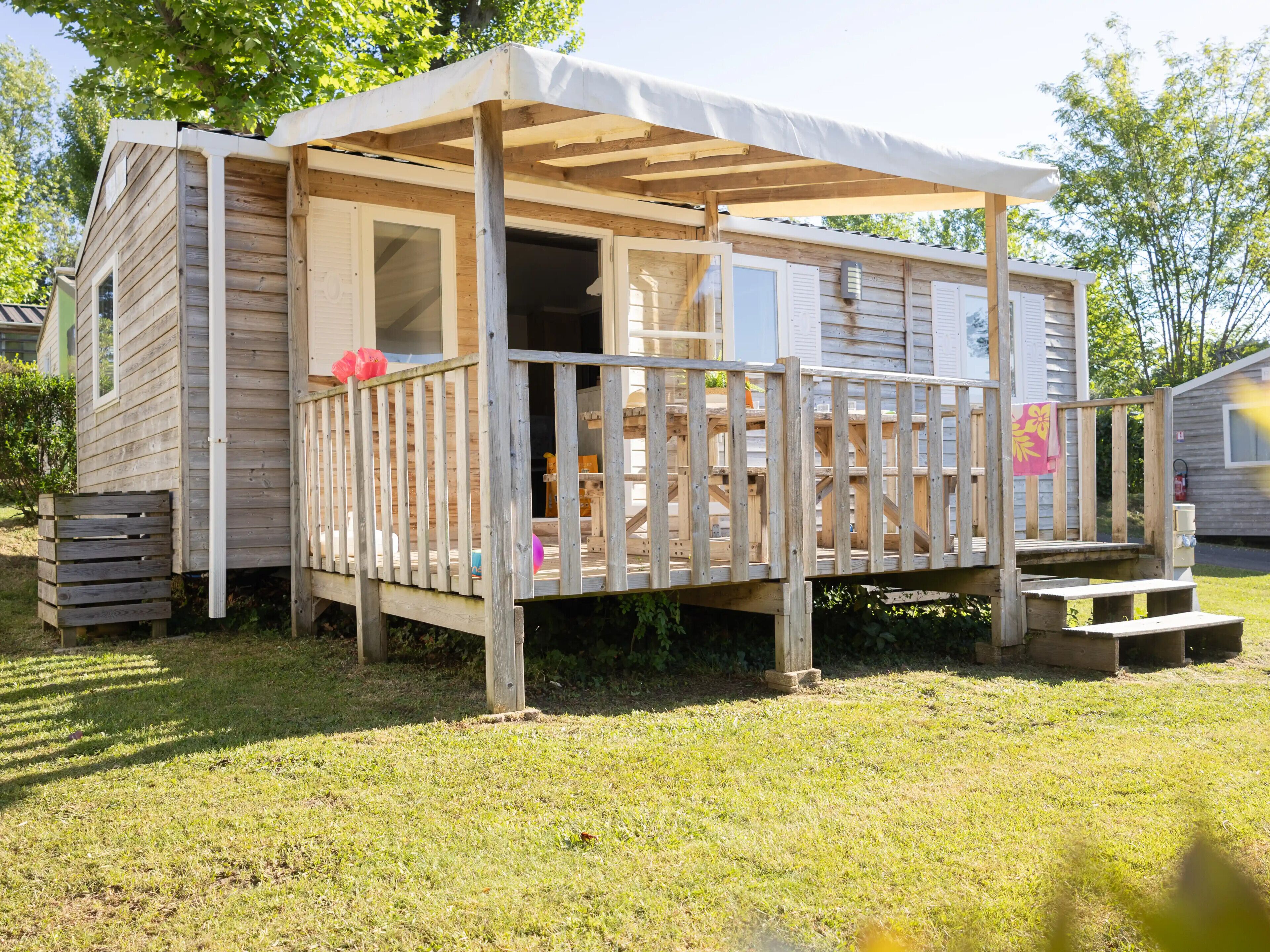 A wooden cabin with a porch, a small deck, and a covered area.