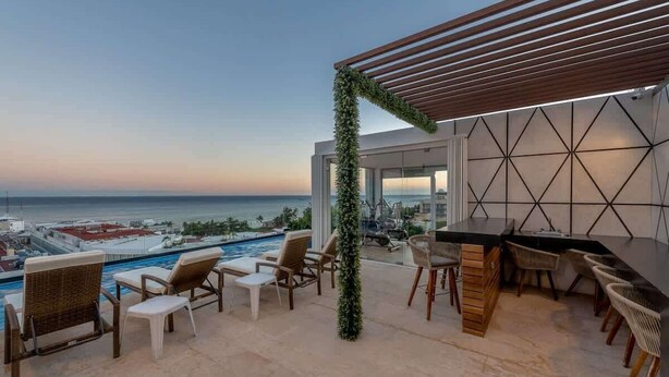 A rooftop terrace with a pool, outdoor seating, and a view of the ocean. - Modern Studio with Patio near 5th Avenue & Beach (Playa del Carmen)