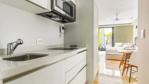 A modern kitchen with a built-in microwave, a stainless steel sink, and a flat-screen TV. - Modern Studio with Patio near 5th Avenue & Beach (Playa del Carmen)