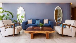 A living room with a blue sofa, two armchairs, a wooden coffee table, and two large mirrors on the walls. - The Boat King Studio 200m to Beach w Rooftop Pool (Playa del Carmen)