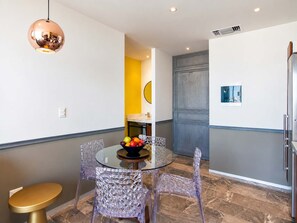 A modern dining area with a round glass table, clear chairs, and a fruit bowl. - 1BR in Singular Joy, best location in town (Playa del Carmen)