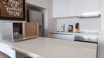Cocina moderna con armarios blancos, microondas integrado, cafetera y bloque para cuchillos.