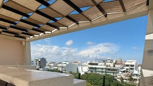 An outdoor terrace with a concrete bar area and a view of a cityscape. - Modern Studio Steps from Beach w/ Rooftop Pool (Playa del Carmen)