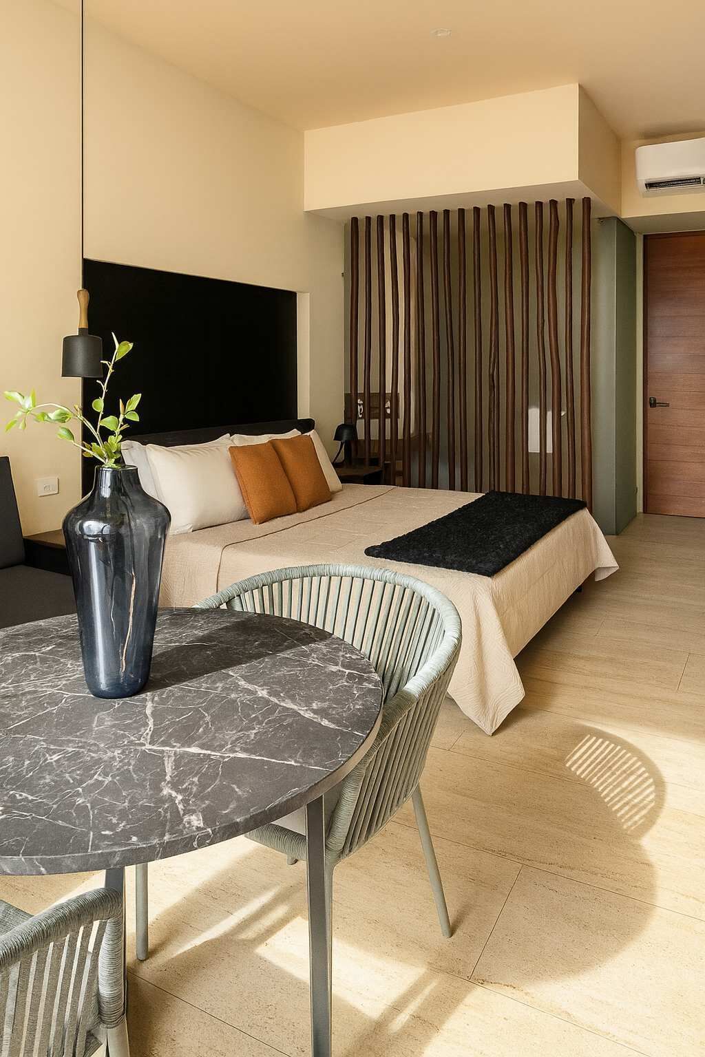 A modern hotel room with a bed, a dining table, and a chair.
