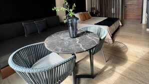A modern living room with a round marble table, grey upholstered chairs, a dark sofa with cushions, and a large window. - Modern Studio Steps from Beach w/ Rooftop Pool (Playa del Carmen)