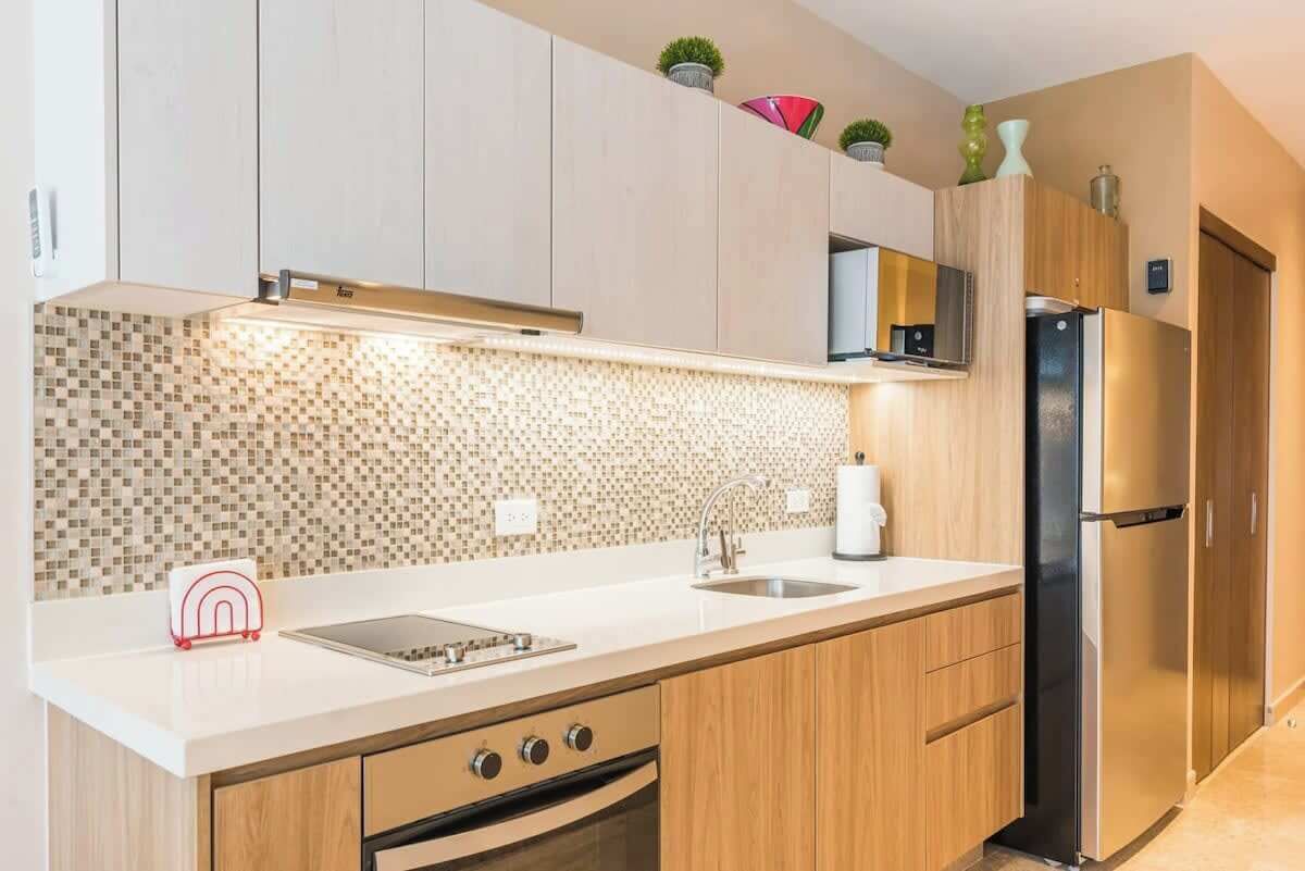 Een moderne keuken met een betegelde spatwand, roestvrijstalen apparatuur en houten keukenkastjes.