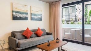 A modern living room with a grey sofa, two red cushions, a wooden coffee table, and two abstract paintings on the wall. - Beach 1BR w Balcony, Washer & Rooftop Pool (Playa del Carmen)