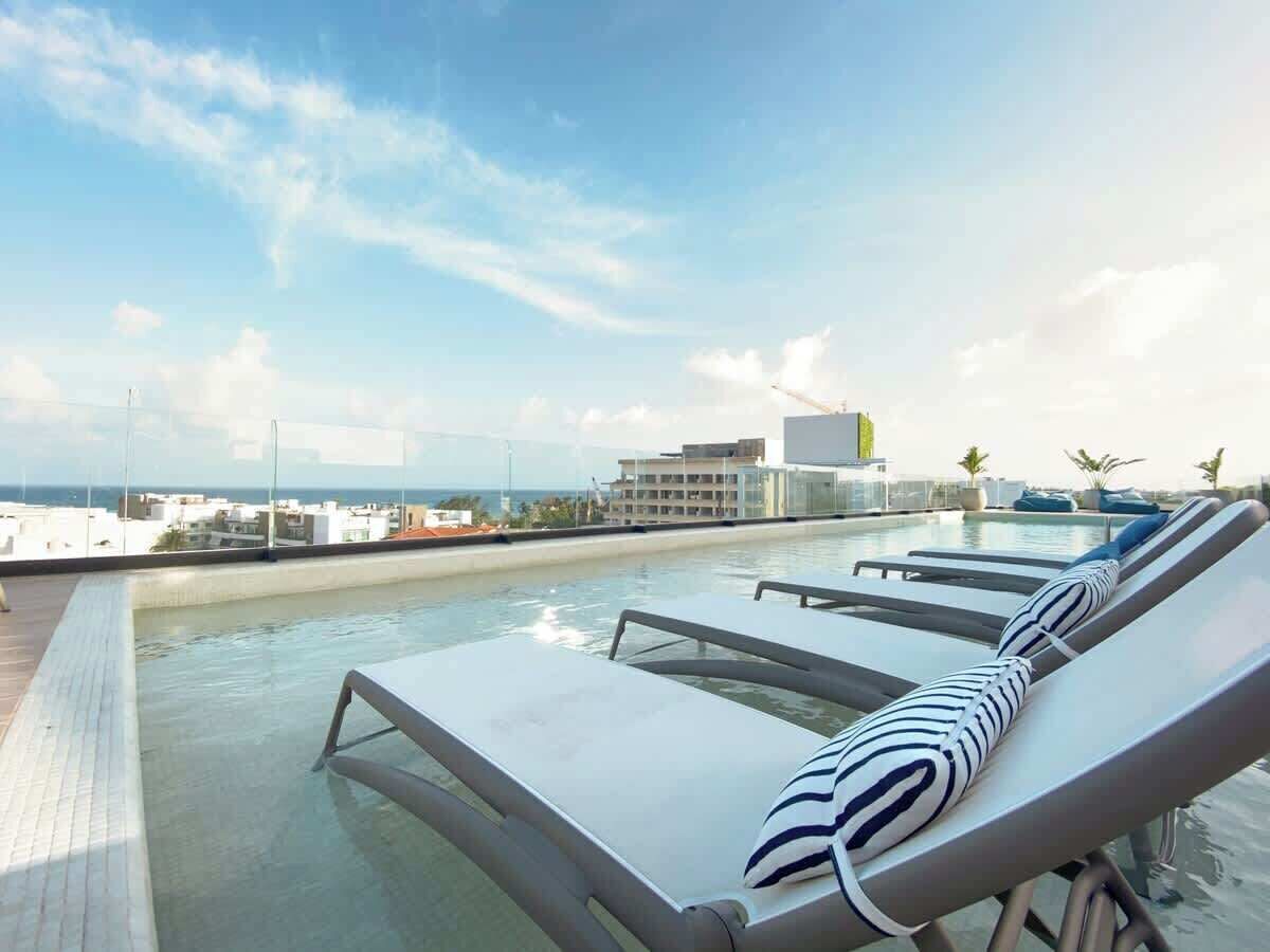 Uma área de piscina no terraço com espreguiçadeiras e vista desobstruída da cidade.