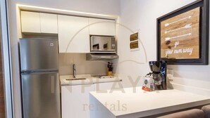 Et moderne køkken med indbygget mikroovn, stålfarvet køleskab og kaffemaskine på bordpladen.