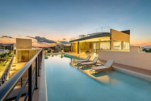 Une piscine sur le toit, dotée de chaises longues, et un bâtiment moderne avec de grandes fenêtres.