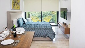 A modern bedroom with a bed, a dining table, and a TV. - Beautiful view Studio near Beach (Playa del Carmen)